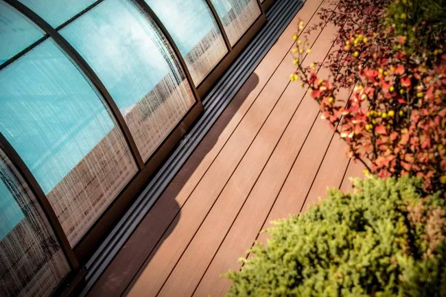Completed WPC Plastic composite terrace installation by a pool enclosure